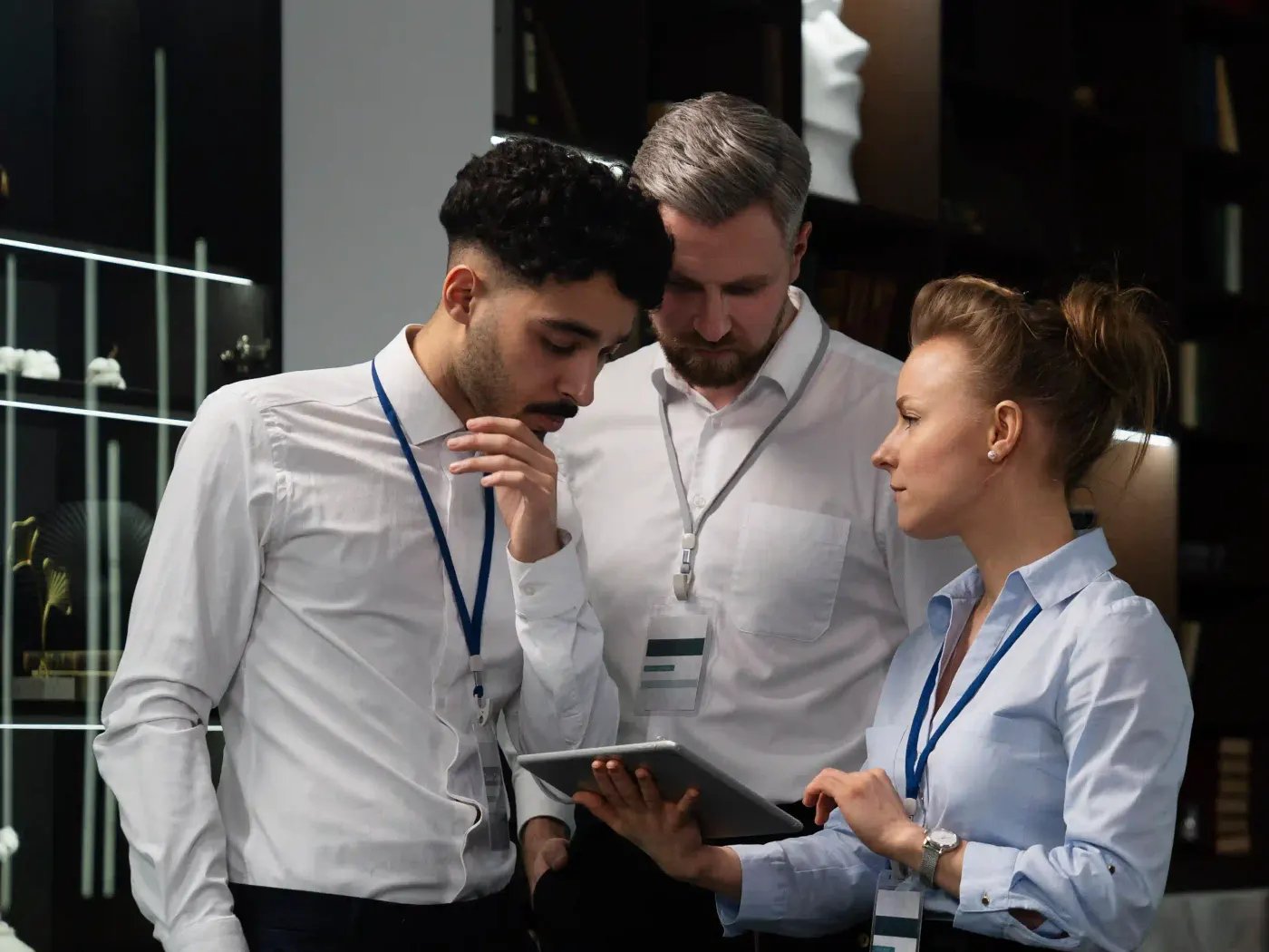 Three security consultants in an office reviewing a plan on a tablet